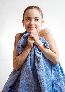 游泳后穿着蓝毛巾的可爱女孩肖像图片