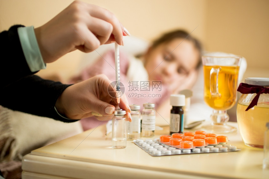 在病人和床旁用药物从丸中抽充注射器的妇女宏观镜头