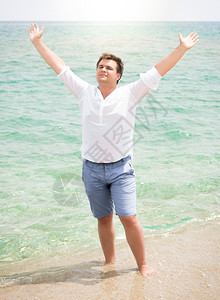 穿白衬衫的帅哥享受海洋举起手在天空中来图片