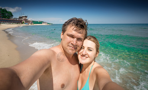 欢快的情侣在阳光明媚的天在海滨做自拍图片