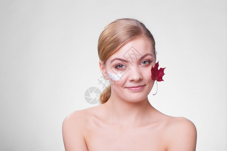皮肤习惯年轻女面孔灰色上以叶子作为红毛皮的标志女孩用湿润奶油照顾干燥的皮肤美容治疗图片