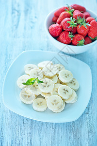香蕉草莓在盘上和桌子图片