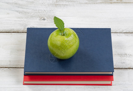 健康绿色苹果在书本上加生锈的白木背景返校教育概念图片
