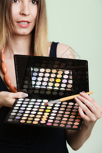 化妆美容程序和概念女拥有专业调色板和刷子的化妆品配饰工具的化妆品绿色背景图片