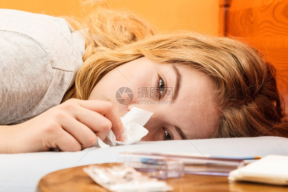 躺在床上的生病女人在组织里打喷嚏女孩得了感冒药片和温度计在桌子上图片