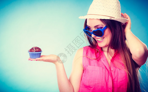 欢乐的夏天时装女人穿着草帽心戴墨镜的手持蓝底蛋糕图片