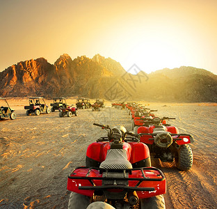 日落时在沙漠中行驶的汽车群高清图片