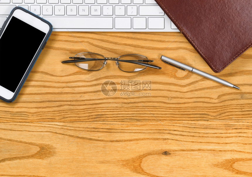 电脑键盘笔记夹的顶端视图在桌面上阅读眼镜笔和手机图片