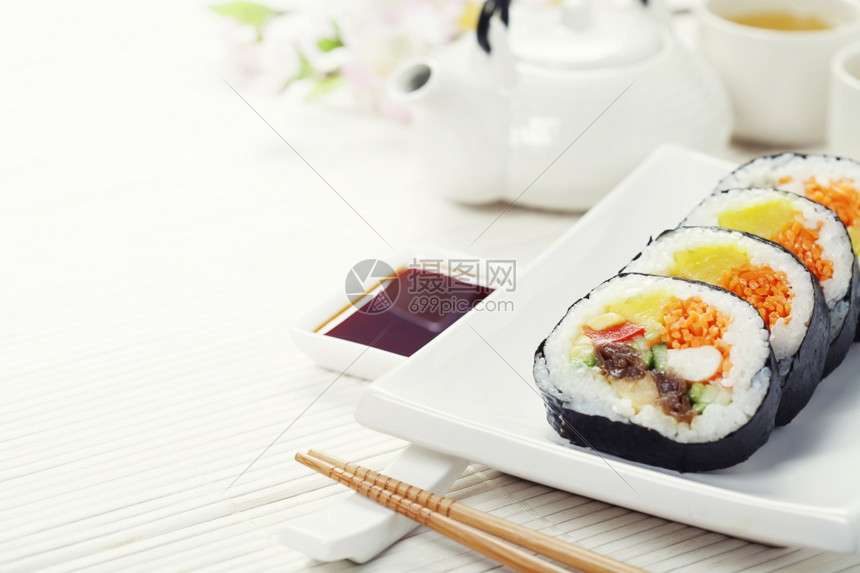 寿司绿茶和竹垫上的樱树枝图片