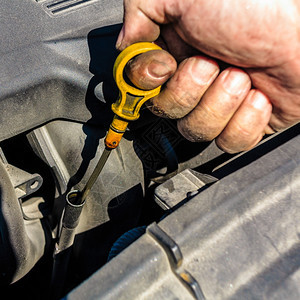 一名汽车机械师在例行维修期间检查汽车发动机的石油水平图片