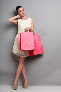 穿着红纸购物袋的全优雅的士光亮裙子买衣服销售和零背景图片