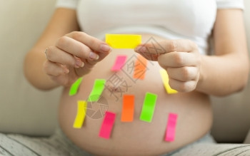 持有彩色备忘标签的年轻孕妇图片
