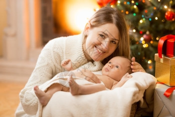快乐的年轻母亲肖像在圣诞节装饰的房子里与新生男婴一起在家中装饰图片