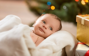 坐在米垫毯下可爱新生婴儿的近视肖像图片