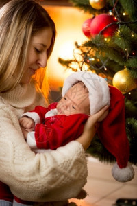 在壁炉里穿着圣诞老人服装的母亲和婴儿肖像图片