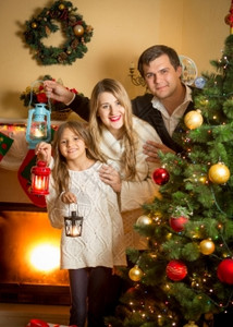 圣诞树上装着灯笼的幸福家庭肖像图片