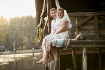 快乐笑的新娘和郎在森林湖边的木码头上放松图片