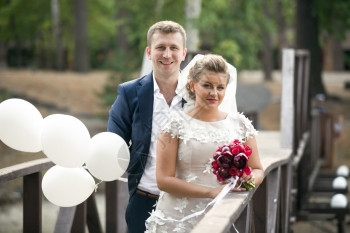 快乐笑的新婚夫妇肖像在桥上冒着白气球图片