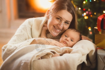 穿着毛毯的婴儿母亲和男孩在圣诞节房间里摆着图片