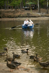 美丽的浪漫新婚夫妇在森林湖边划船图片