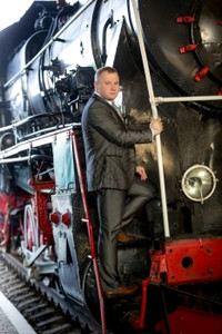 高贵的男人坐在旧蒸汽列车的楼梯上图片