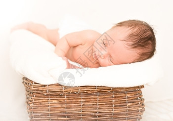 睡在被毯子覆盖的旧篮里可爱新生婴儿男孩图片