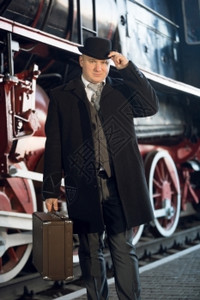 穿旧式西装保龄帽子和手提箱的男肖像图片