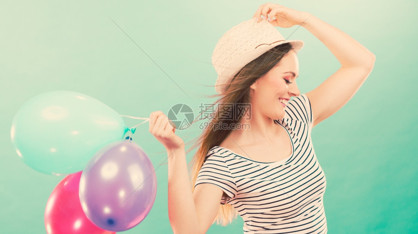 快乐的女孩玩多彩气球幸福和快乐夏天年轻有魅力的快乐女人戴着草帽带多彩的气球绿色背景图片