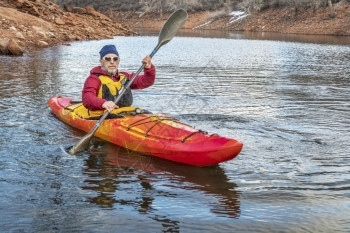 高级男正在一个平静的湖泊上划着多彩的河皮艇娱乐概念图片