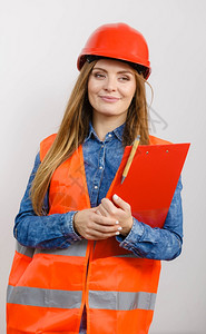 女建筑工人结构程师穿橙色背心红硬头盔的建筑工结构程师持有笔文件垫工业作安全室中图片