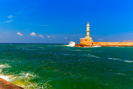 在希腊克里特的夏日阳光明媚子里波浪冲向古希尼亚港的灯塔图片