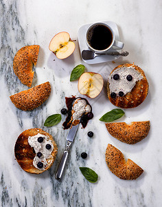 用奶油酪酱汁蓝莓巴西尔切苹果和白大理石上的咖啡加烤面包圈的俯瞰图片