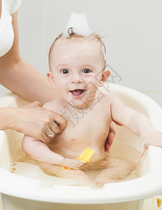 喜笑的男孩用泡沫洗澡的肖像图片