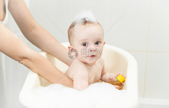 年轻母亲在塑料浴池中洗澡的年轻母亲图片