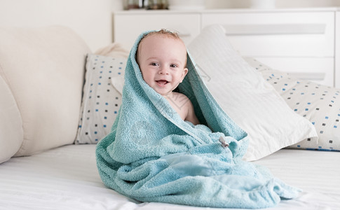洗完澡后带着蓝毛巾的婴儿笑着快乐图片