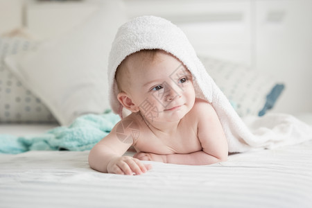 九个月大的快乐婴儿肖像洗澡后在毛巾下看着图片