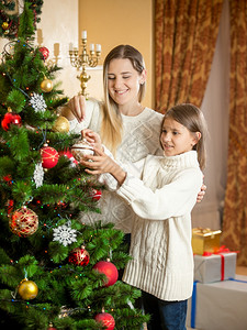 喜悦的母亲肖像与女儿装饰圣诞树图片