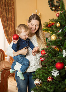 快乐的笑母亲和小男孩装饰圣诞树和图片