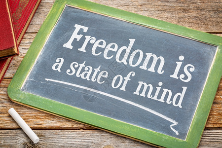 自由是一种思想状态鼓舞人心的文字在黑板上用白粉和一堆书与生锈的木制餐桌相对图片