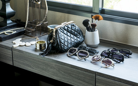 黑桌上的手袋太阳眼镜首饰和化妆刷图片