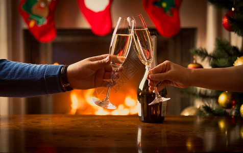男人和女的手与香槟杯相缠在装饰圣诞的客厅图片