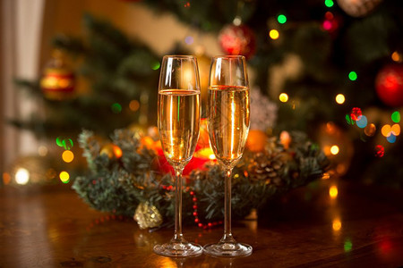 两杯香槟和圣诞花圈木桌上有蜡烛图片