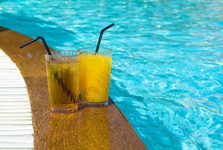 一杯橙汁加冰对游泳池图片