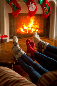 家庭在燃烧的壁炉旁坐着穿编织袜子的家庭图片