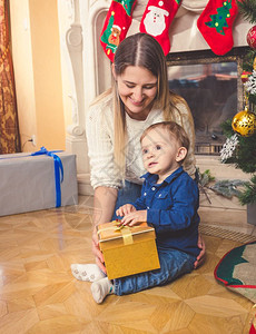 微笑的母亲和她儿女在客厅地板上拿着圣诞礼物微笑着的母亲和她儿女图片