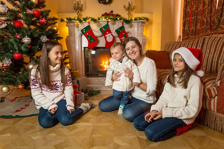 圣诞节在壁炉旁边的地板上母亲小儿子和两个女图片