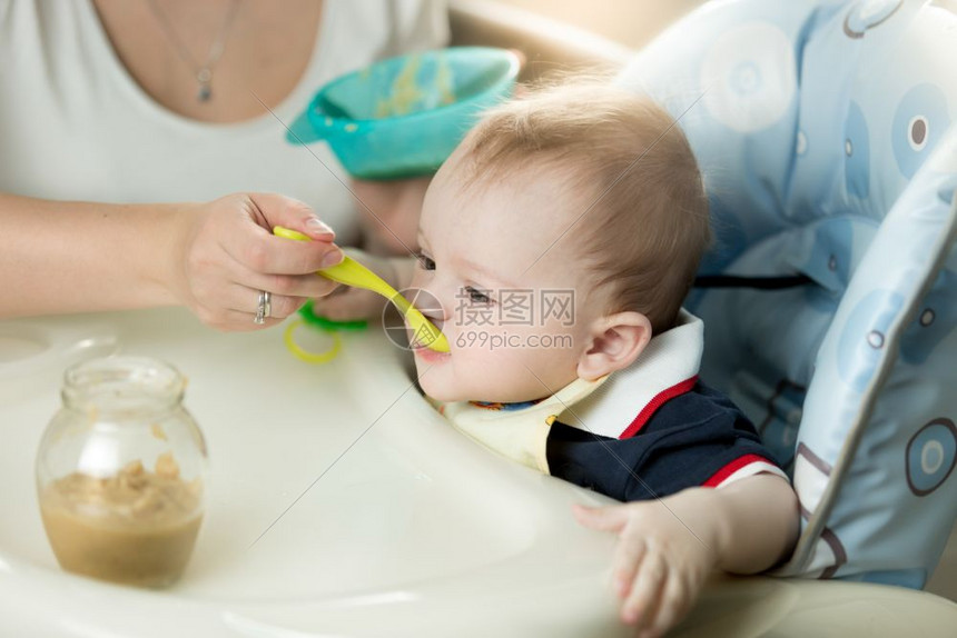 年轻母亲用高椅子喂婴儿图片