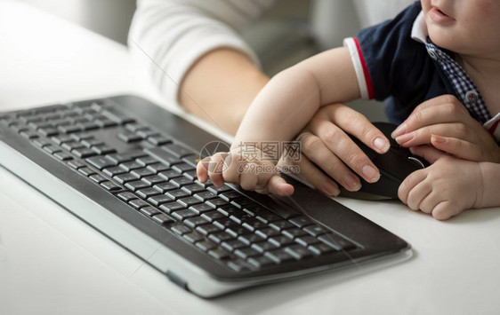 婴儿男孩在计算机工作时坐在母亲的膝上可爱男孩子图片