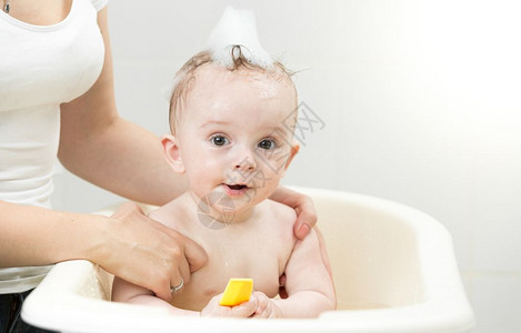 与黄橡皮鸭一起在泡浴中玩的可爱男孩图片