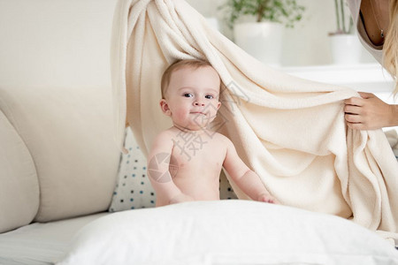 母亲在床上用白色大毯子罩着她的婴儿男孩图片